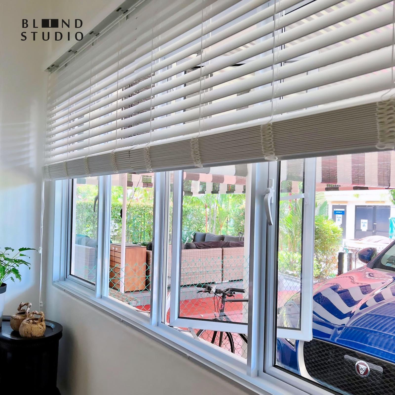 White venetian blinds facing a blue Jaguar car